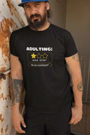 Adulting Unisex Softstyle T-Shirt with one-star review print design worn by a man, showcasing casual comfort and style.