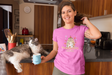 Meeyowy Christmas Women's Softstyle T-shirt with cat graphic, worn by a smiling woman in a kitchen.