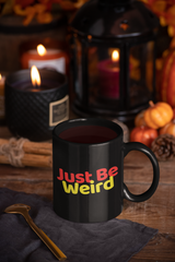 "Weird 11oz Mug" in black with colorful text, ceramic, 11 oz capacity, C-handle design.