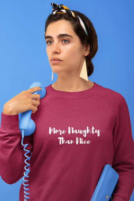 More Naughty Than Nice unisex sweatshirt in pink, worn by a woman with a blue telephone receiver.