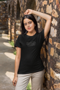 Women's dark t-shirt with "Just Be Weird" design, soft style, outdoor setting.