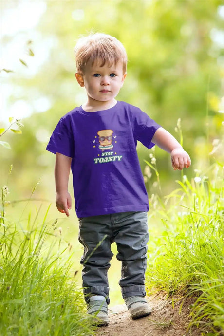 Toddler wearing a Stay Toasty Kids Softstyle T-Shirt in a grassy path.